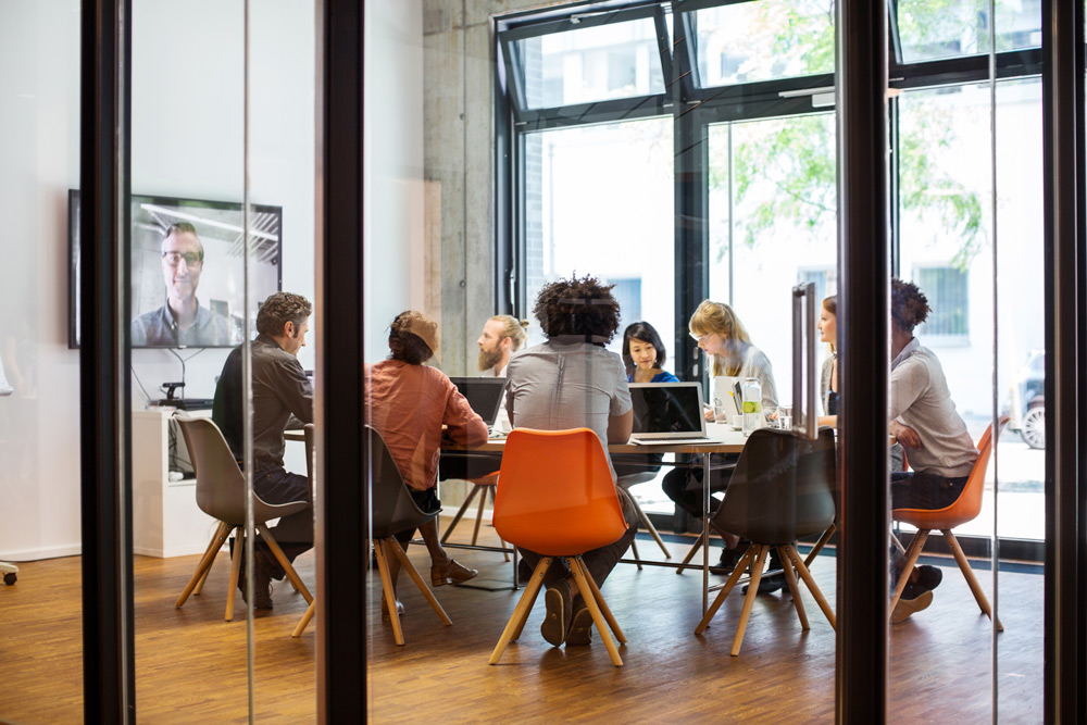 Ett affärsmöte med flera personer som sitter runt ett bord på ett kontor